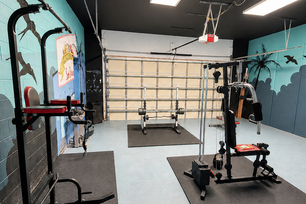 Indoor gym with free weights, a squat rack and a cable machine at the Sweet Escape vacation home near Orlando